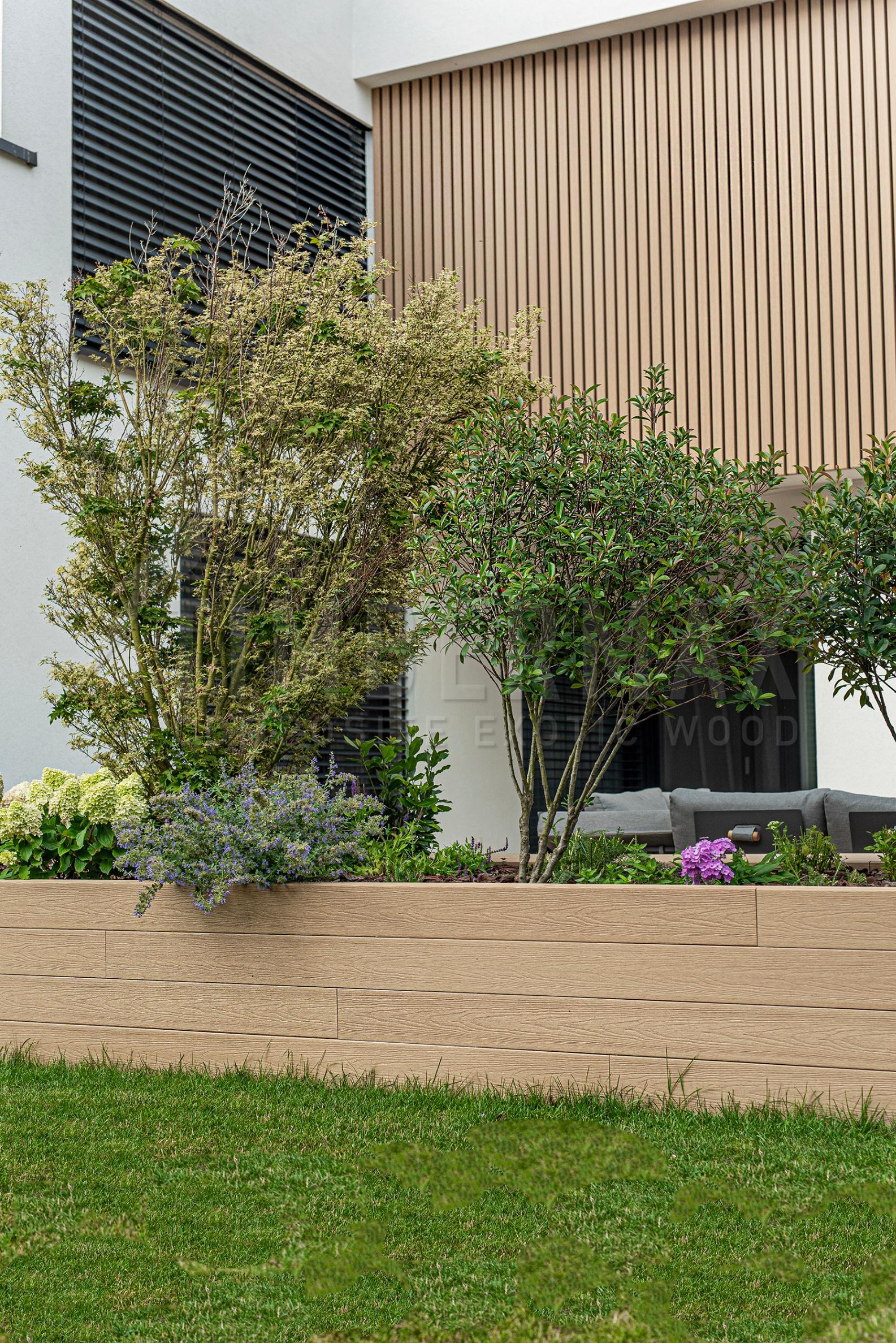 flower bed in front of the house with a slatted facade in the background
