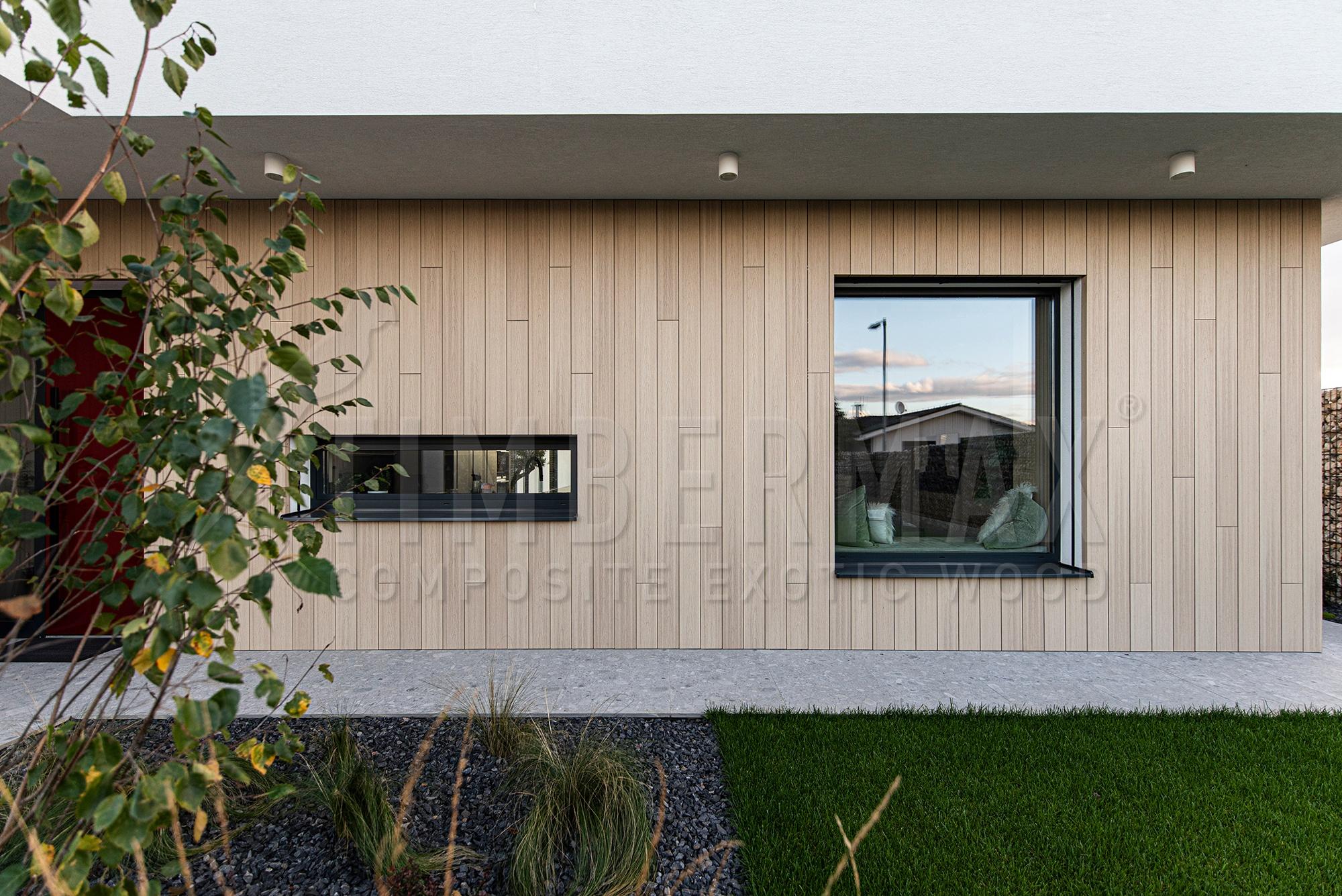 Zvislá fasáda rodinného domu s dvojicou okien a záhradnou výsadbou