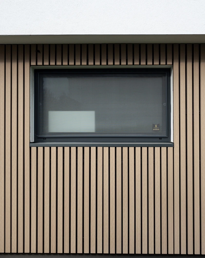 Vertikale Timbermax P60 Fassadenlamellen an einem dunklen Fenster, Referenzprojekt Jazdecká.